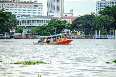 Boats in river by buildings in city