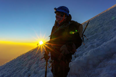 Man standing on snow covered mountain during sunset