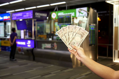 Cropped hand of woman holding paper currency in mall