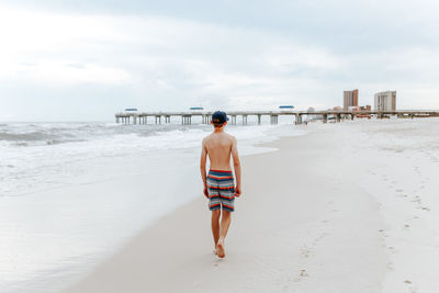 Rear view of teenage boy standing on beach