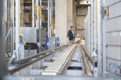 Businessman at conveyor belt in factory