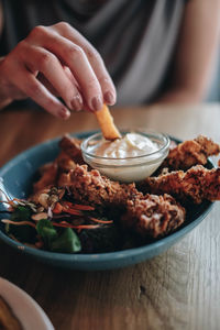 Close-up of hand holding food in bowl on table