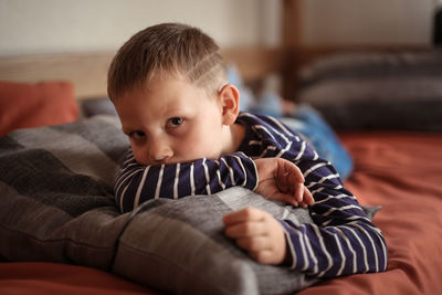 Thoughtful serious offended boy hugs a pillow on the couch, concept children's problems  loneliness.