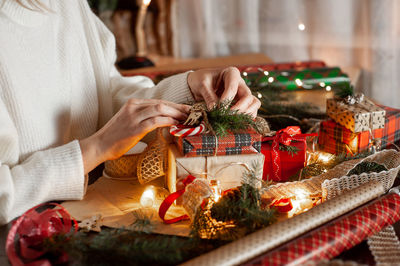 Women's hands decorate the box with the christmas gift. table with decor and materials 
