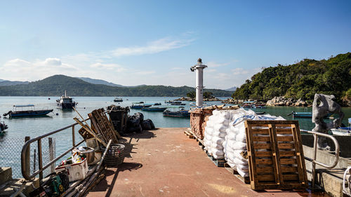 People at harbor by sea against sky