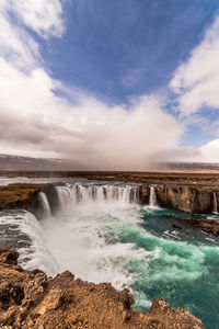 Scenic view of waterfall against sky