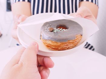 Midsection of giving donut to person