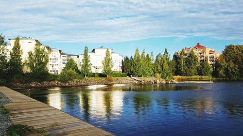 Scenic view of river by buildings against sky