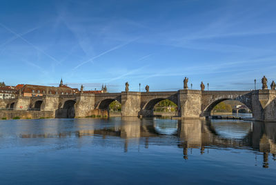 Arch bridge over river against blue sky