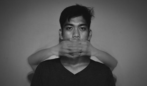 Portrait of young man standing against wall