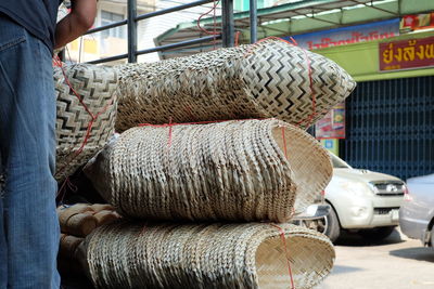 Midsection of vendor standing by wicker basket bundles at market stall