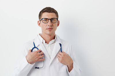 Portrait of doctor holding stethoscope against white background