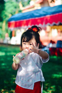 Portrait of girl blowing bubbles while standing outdoors