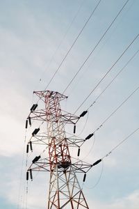 Low angle view of electricity pylon against cloudy sky