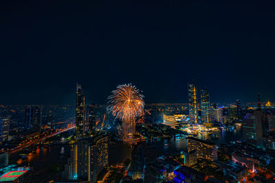 Firework display over city lit up at night. high angle view of illuminated buildings 