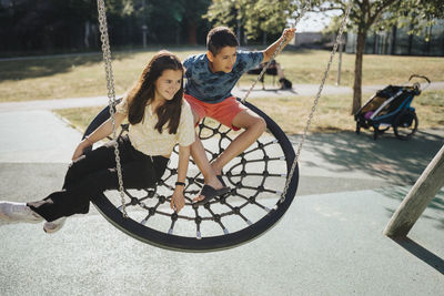 Siblings having fun swinging on swing on playground