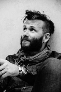 Close-up of man looking up while sitting against wall