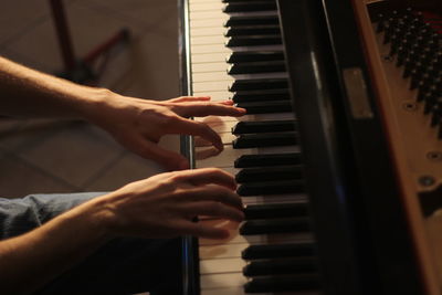 Cropped image of man playing grand piano during sunset