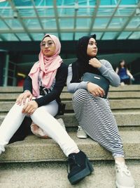 Full length of young women sitting on steps