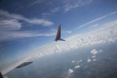 Airplane flying over landscape against blue sky