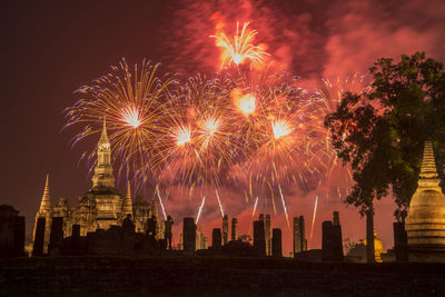 Low angle view of firework display in city against sky at night