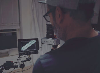 Rear view of photographer looking at monitor in studio