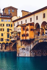 Arch bridge over canal against buildings in city