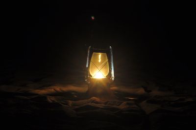 Close-up of illuminated light bulb against black background