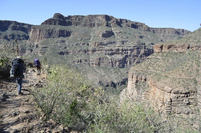 Rear view of man on rocky mountains against clear sky