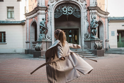 Rear view of woman walking in temple against building