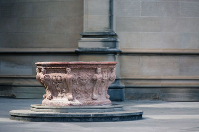 Old carved pedestal on street against wall