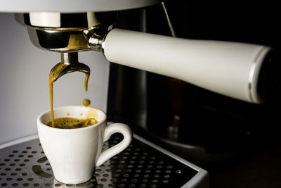 Coffee flowing from machine to cup at cafe