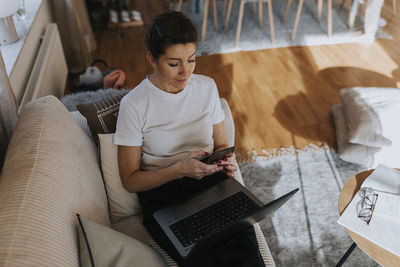 Woman using cell phone on sofa