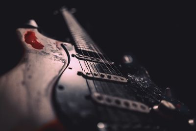 Close-up of hand playing guitar against black background
