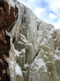 Low angle view of icicles on rock against sky