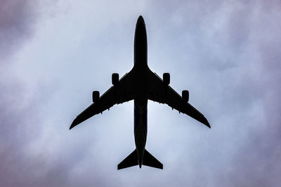 Low angle view of silhouette airplane flying against sky