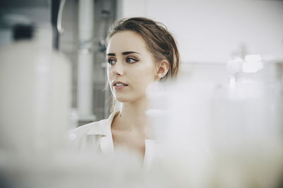 Confident young female student looking away while standing in laboratory