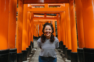 Portrait of smiling young woman standing outside temple