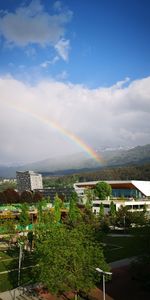 Rainbow over buildings in city against sky