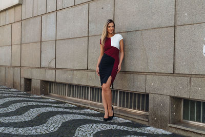 Woman looking away while standing against building