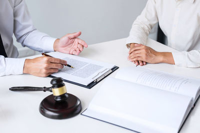 Midsection of lawyer and client having meeting at desk in courtroom