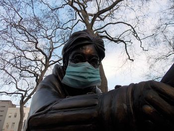 Low angle portrait of man against bare tree