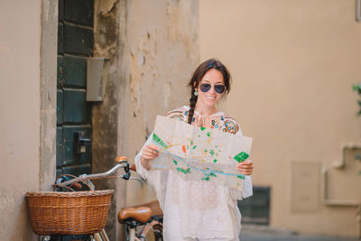 Portrait of young woman standing against wall