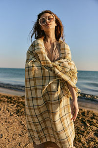 Young woman standing at beach against sky