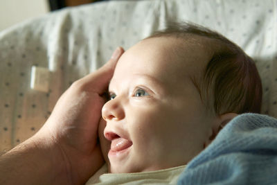 Close-up portrait of baby girl lying on bed at home