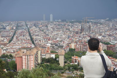 Rear view of man and cityscape against sky