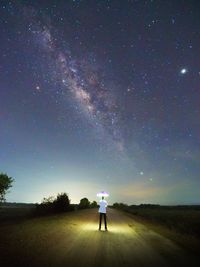 Rear view of man standing on road against star field