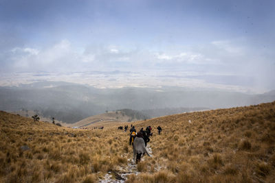 Rear view of people on landscape against sky