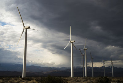 Windmills on field against cloudscape