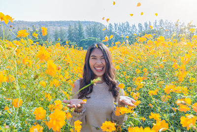 Young woman with yellow flowers on field